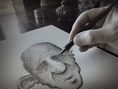 Adam Elliot at work. A grey scale close up of a face with a bald head, closed eyes and huge ears, being drawn with a pen and hand completing the drawing.