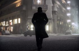 Ryan Gosling in a still from ‘Blade Runner 2049’ (2017), directed by Denis Villeneuve. Gosling is shown in silhouette, walking across a snowy street in a future, climate-impacted Los Angeles. Artworks from Blade Runner 2049 are showing at ACMI in the exhibition The Future & Other Fictions.