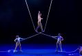 One Fell Swoop Circus has welcomed the news that the Perry Street, Collingwood training facility will remain a home for circus and physical theatre artists. Two circus artists stand on a blue stage, holding overlapping white ropes. A third circus artist balances on the ropes where they are intertwined.