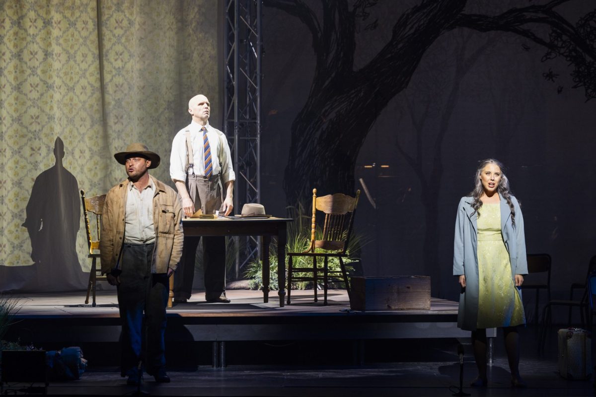 Three opera singers in Eucalyptus, a bushman in an Akubra, a farmer in shirt, tie and braces, and a young woman in a green dress and light blue coat. Michael Petruccelli, Simon Meadows and Desiree Frahn