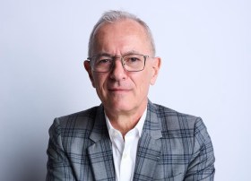 man with short grey hair and glasses wearing checked suit. Michael Brand