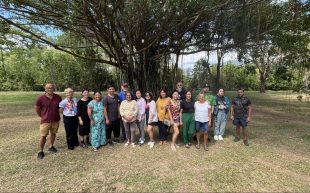 The ‘Linear Horizons’ cohort in Gimuy/Cairns, taking part in a First Nations and Filipino printmaking initiative. In the photo is a group of 17 people standing under a large tree outside.