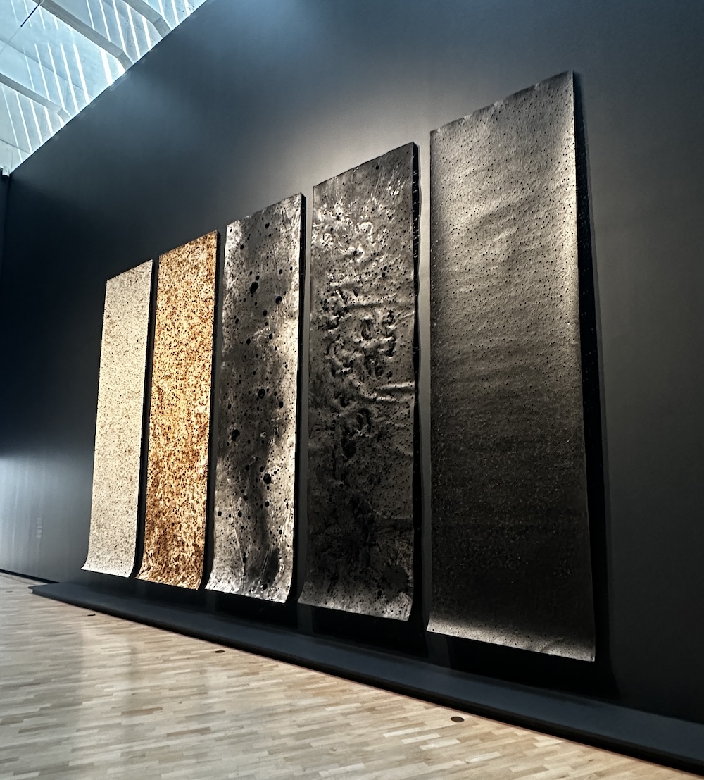 Five scroll like long drawings on a black wall in a gallery setting. Lindy Lee.