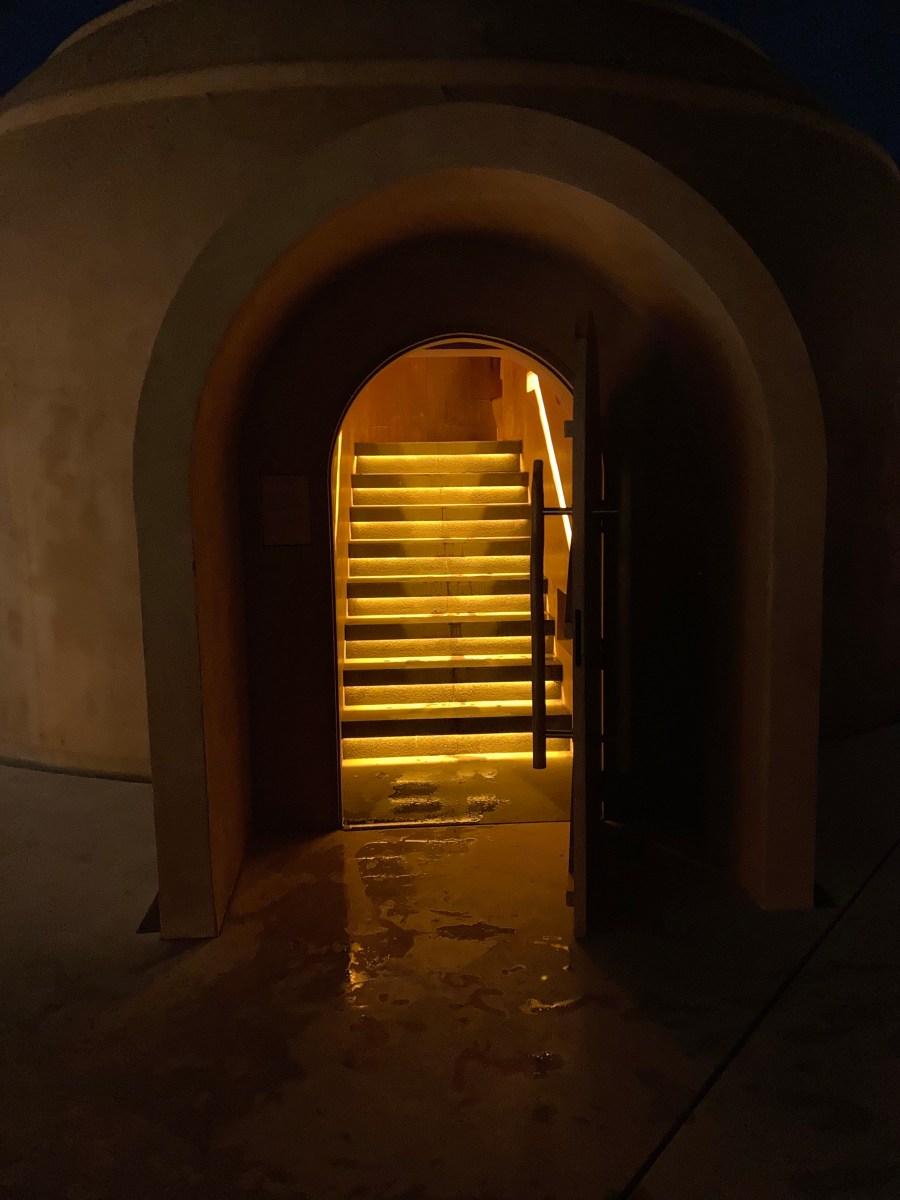 A treatment sauna dome in sand coloured concrete, lit within. Nuanu