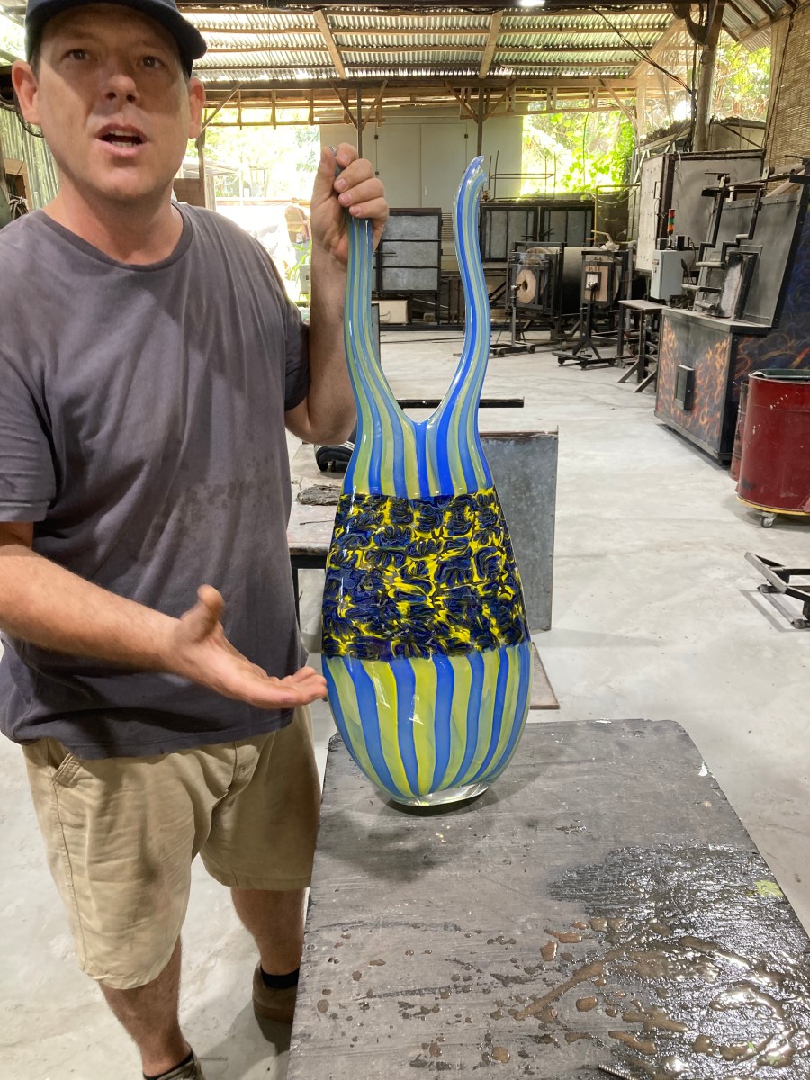 A man holds a multi coloured glass vase. Nuanu