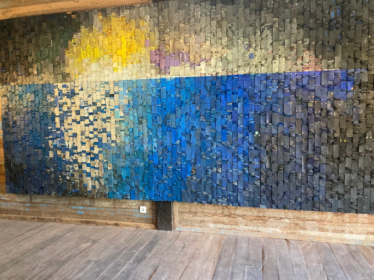 large blue, yellow and grey artwork made from discarded plastic footwear. Nuanu