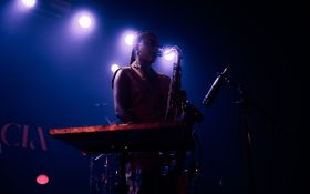 Nubya Garcia at 170 Russell Street performing as part of Melbourne International Jazz Fest 2024. A Black woman on stage playing the saxophone with purple lights behind her.