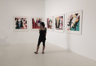 Woman dressed in black looking at art in white galelry space.