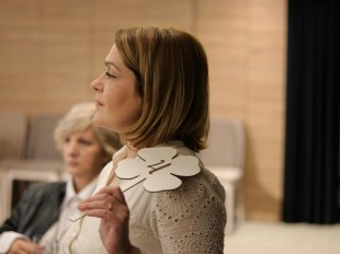 woman dressed in white holding an auction bidding paddle.