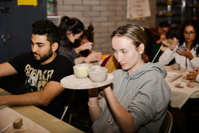 Girl in grey sweatshirt in pottery workshop.