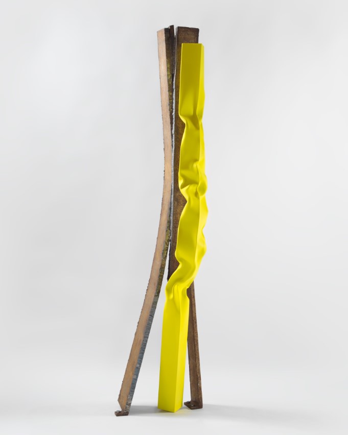 An upright artwork, split into three, one piece of which is a slightly crumpled yellow piece of stainless steel. 