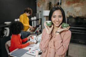 Woman holding up ceramic cups made in workshop.