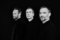 Iceland's Sigur Rós will perform a series of orchestral concerts in Australia in May 2025. Three white men pose in black against a black background.