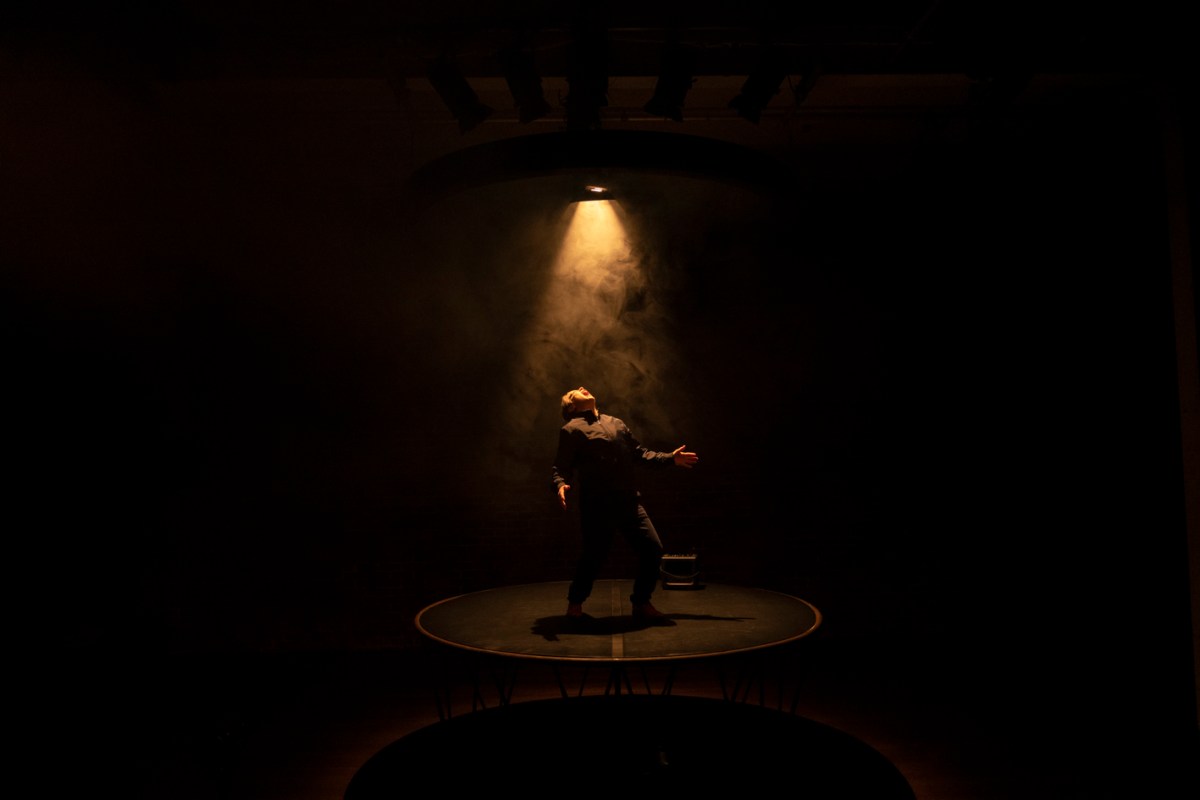 The stage is dark except for a spotlight shining over Nicci Wilks in the production of 'BAD BOY".