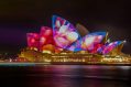 A shot of Sydney Opera House at night, with colourful projections on its sails.