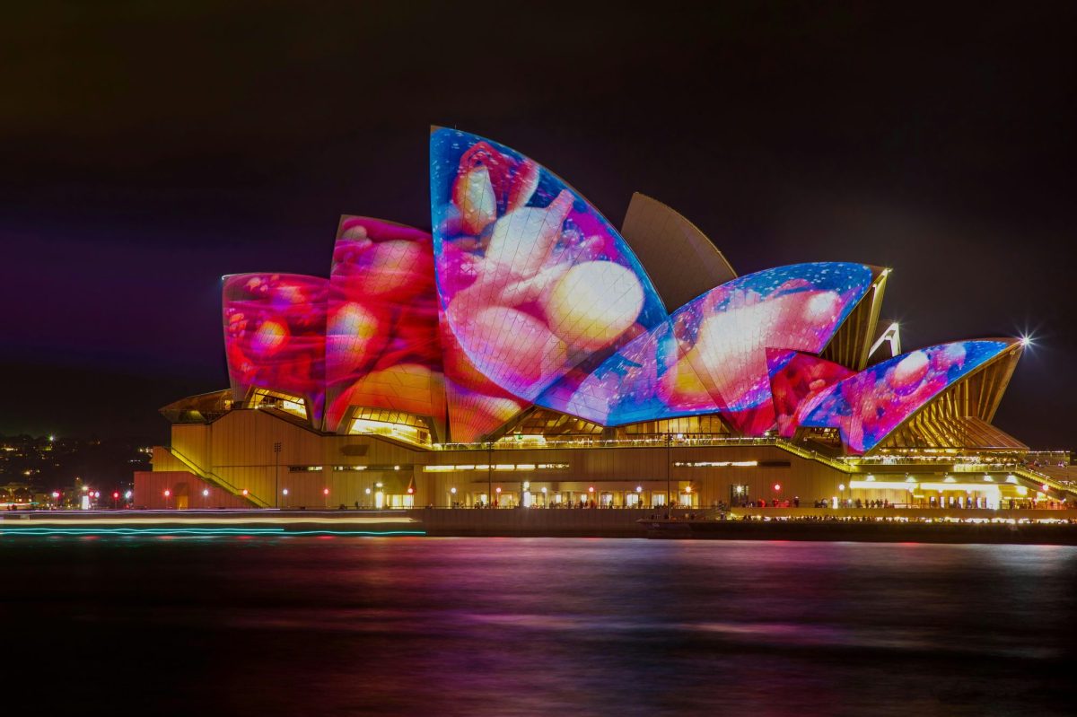 A shot of Sydney Opera House at night, with colourful projections on its sails.