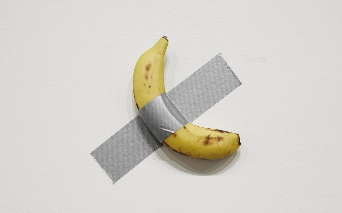 Installation view of Maurizio Cattelan's 'Comedian', 2019, on display in NGV Triennial 2023. A single banana duct-taped to a white wall.