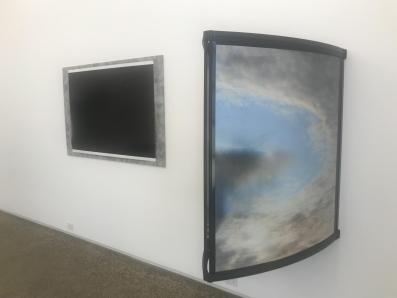 Two pieces of artwork by Chloe Nolan. One looks like a black canvas framed. The other sticks out form the wall and features a sky view.