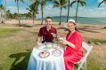 Happy image of woman in red dress and man in t-shirt having a tea party in tropical location. Wedgwood