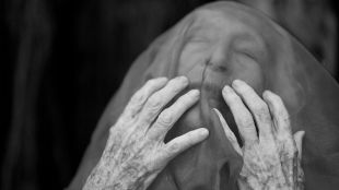 Eileen Kramer in the forthcoming Sydney Festival production 'AFTERWORLD'. A 110-year-old woman holds her hands to her veiled face.