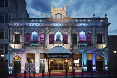 Façade of Her Majesty's Theatre at night and lit up.