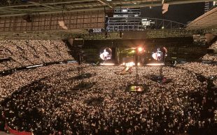 A concert stadium arena with thousands of people wearing light up wristbands. Coldplay