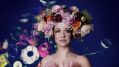 Opera Queensland's 'La Cenerentola (Cinderella)' is the centrepiece of the 2025 Brisbane Bel Canto Festival. A fair-skinned young woman wearing an exaggerated wreath of flowers on her head stands with shoulders bared against a floral background.