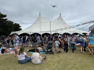 A white tent in a field surrounded by festivalgoers at Queenscliffe Music Festival.