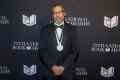 Percival Everett has won the National Book Award for his novel, James. Image is a man in a formal suit standing in front of a media wall.