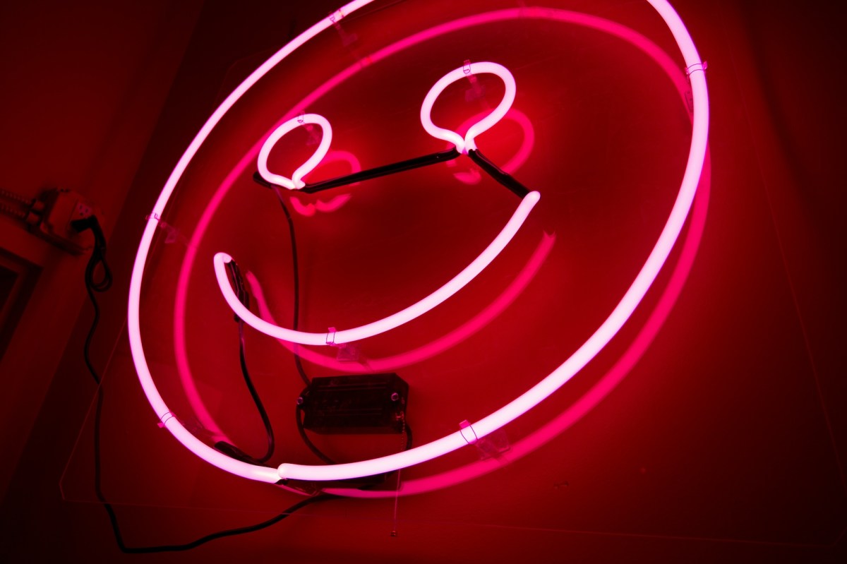 Neon of a red smiley face. Wellbeing