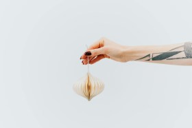 woman's arm with tattoo holding paper christmas decoration