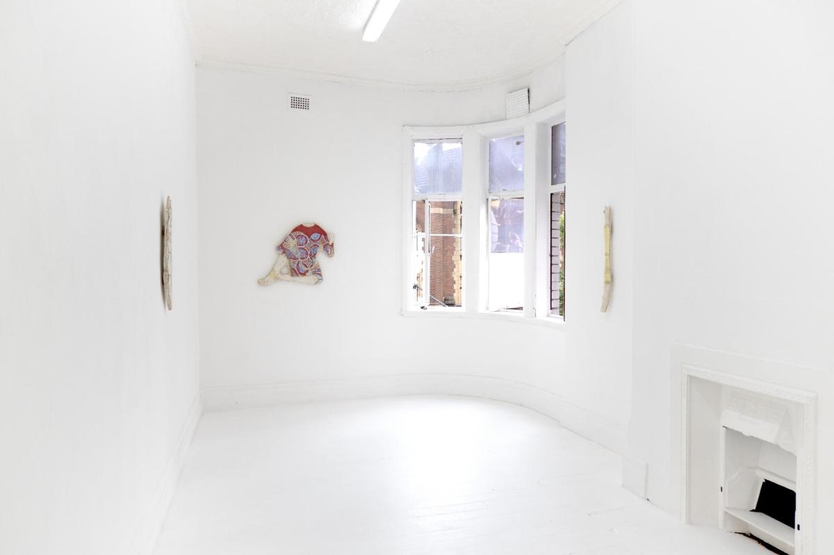 A white room with a window on the right hand side. There's an artwork of a headless torso in the middle of the room.