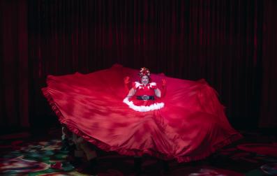 A woman wearing a Santa costume with enormous layers of skirt surrounding her.