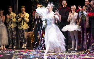 The Australian Ballet, ‘The Nutcracker’, featuring Sara Andrlon, winner of the 2024 Telstra Ballet Dancer Award. A ballerina dressed in white on stage among a crowd of applauding performers.