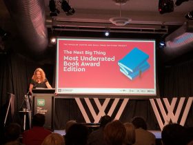 Image of woman (Louise Swinn) at a lectern with signage behind her reading "Most Underrated Book of the Year SPN"