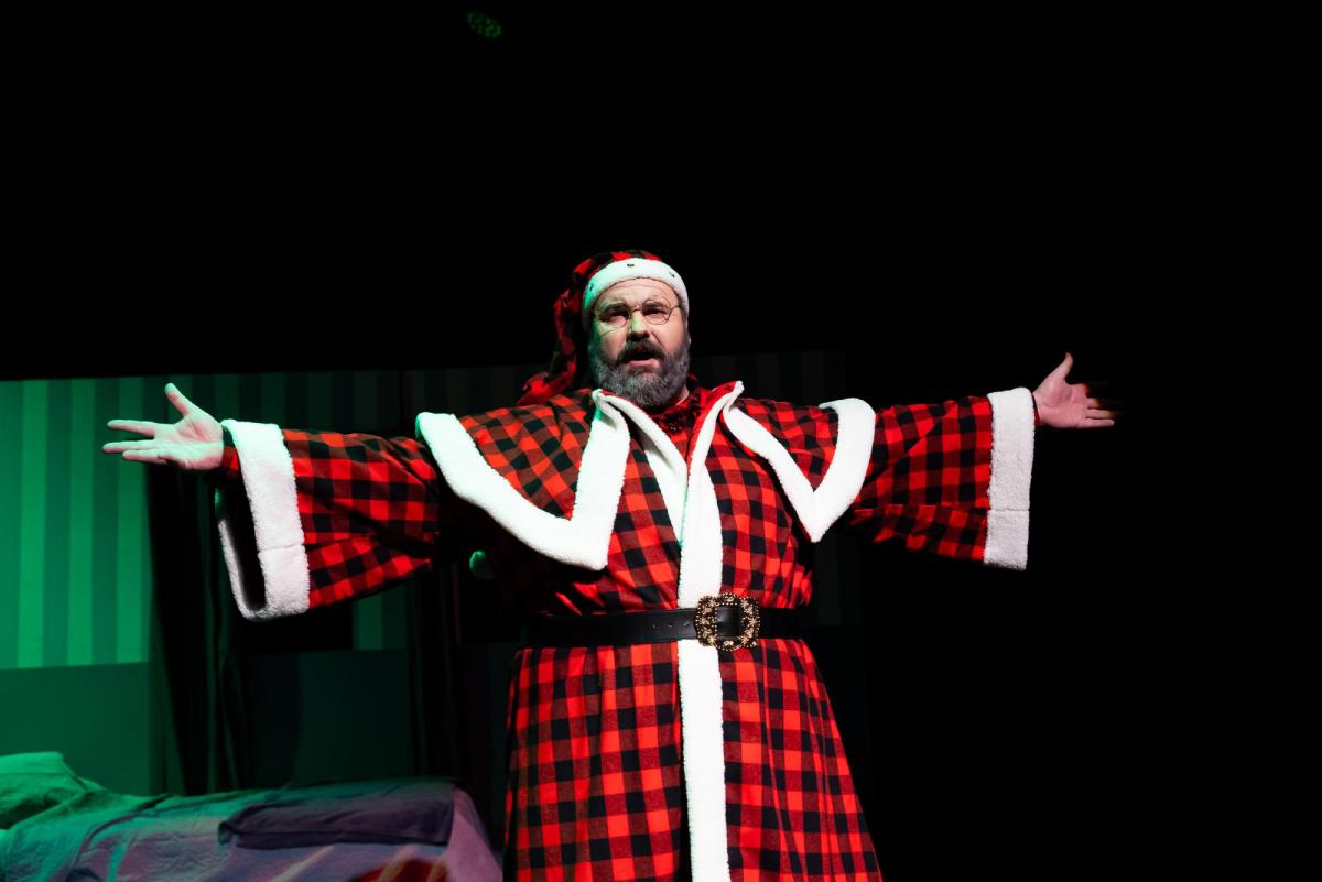 A man dressed in a tartan black and red Father Christmas costume.