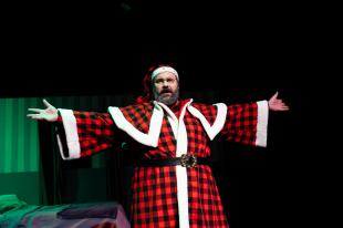 A man dressed in a tartan black and red Father Christmas costume.