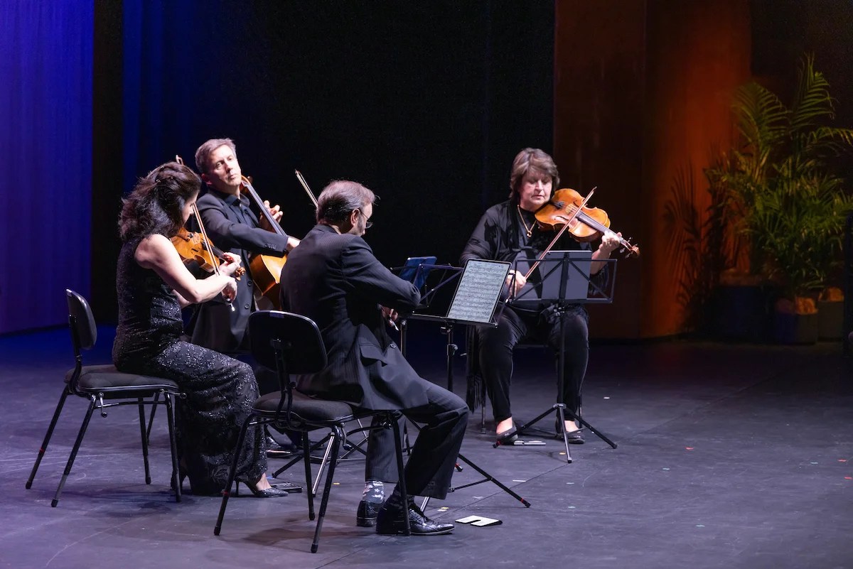  A string quartet play their instruments on a stage.