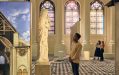 ‘Notre-Dame de Paris: The Augmented Exhibition’ at Immigration Museum. An exhibition space with large panels depicting the architecture of a church and a sculpture of Mary. A person is looking up at the sculpture while two more people behind them are looking at a screen.