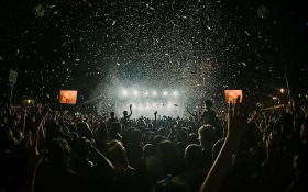 Gold Coast introduces new arts grants. People at a music festival pumping their fits. The air is filled with confetti raining down on them.