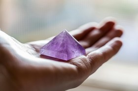 holding a pink pyramid crystal in palm of hand. Gallery representation