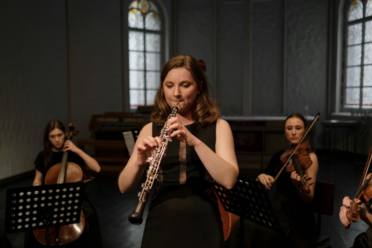 woman leading an orchestra, playing an oboe