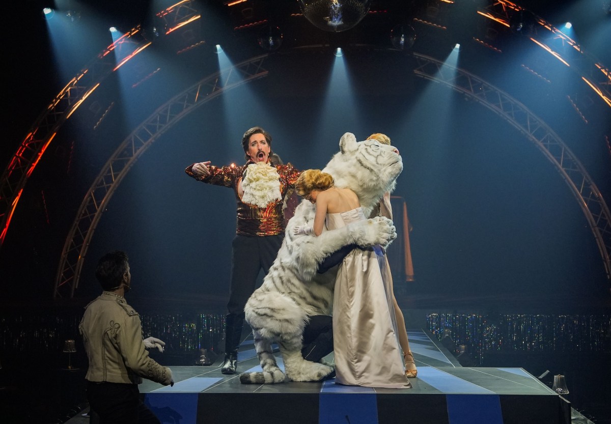 Woman hugging white tiger while man singing. Siegfried and Roy