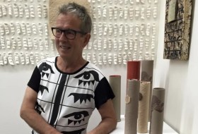 Vale: Sydney artist Michael Keighery died earlier this month. The photo shows an Anglo-Australian man wearing a black and white shirt and glasses standing in a ceramics exhibition.