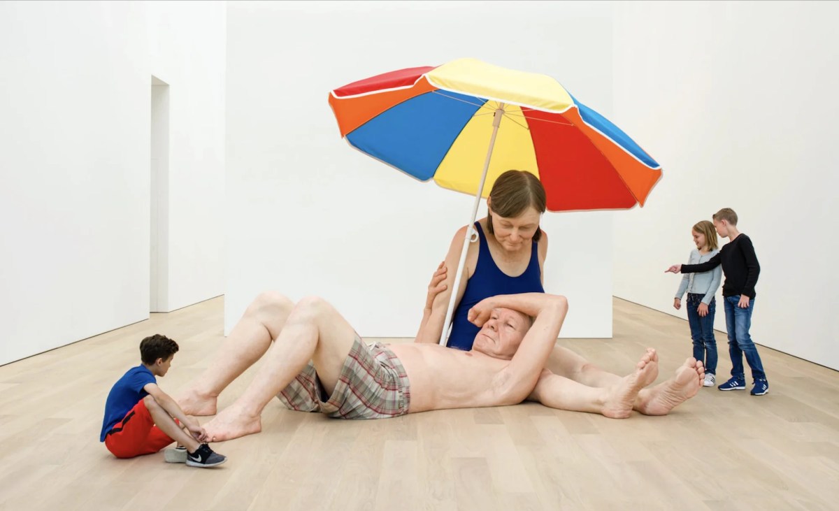 Hyper real oversized sculptures of people in beach scene in gallery. Ron Mueck