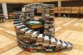 a display of books stacked in a swirling pattern in the middle of a wooden floor. Literary festivals.