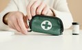 Woman with white top holding a green medical kit. Career toolkit.