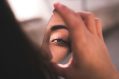 Woman holding mirror and showing reflection of her eye. Arts news.