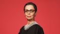 Australian actor Heather Mitchell as Ruth Bader Ginsburg in ‘RBG: Of Many, One’ at HOTA from 3-5 April 2025. A fair-skinned woman, dressed as member of the American judicary, stares somewhat aloofly at the camera. Behind her is a salmon-pink background.