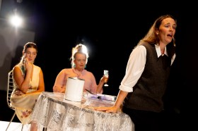 Three women, two are seated and one is standing in a production of 'Anatomy of a Suicide.'